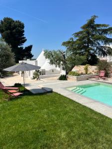 basen z parasolem, krzesłem, stołem i parasolem w obiekcie IL TRULLO BIANCO - Country House & SPA w mieście Castellana Grotte