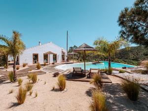 a house with a swimming pool with chairs and an umbrella at Monte de São Marco in Corte Paral