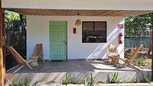 a porch with two chairs and a green door at Hotel Zelen in Tamanique
