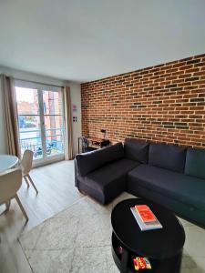 a living room with a couch and a brick wall at La treille Vieux-Lille - 4 pers - Parking in Lille +1 photo
