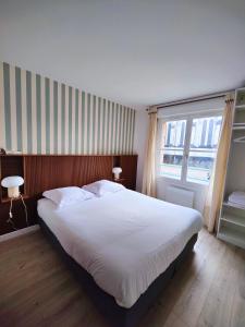 a bedroom with a large white bed with two windows at La treille Vieux-Lille - 4 pers - Parking in Lille