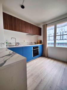 an empty kitchen with blue cabinets and a sink at La treille Vieux-Lille - 4 pers - Parking in Lille