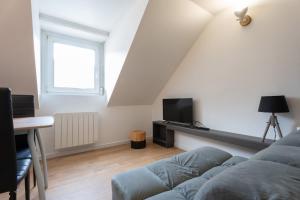 a living room with a couch and a tv at Ideal - Quiet garden - Free parking in Mulhouse