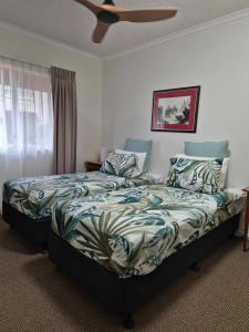a bedroom with a bed with a comforter and a fan at Bulloo Lagoon Oasis Luxury Resort in Cairns North