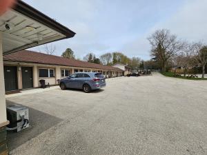 a car parked in a parking lot in front of a building at Forest Plaza Motel in Mount Forest