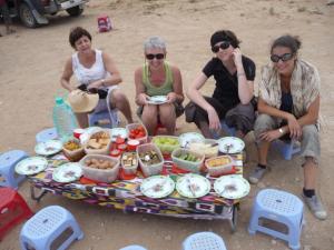 a group of people sitting around a picnic table with food at Nurata Ecotourism Guesthouse in Yukary-Ukhum +25 photos