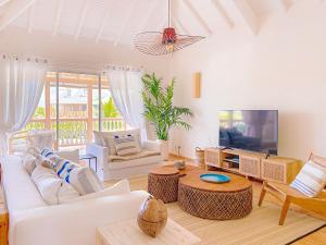 un soggiorno con mobili bianchi e TV a schermo piatto di Sable Bleu Elegant 2-Bedroom Oceanfront Apartment a Orient Bay