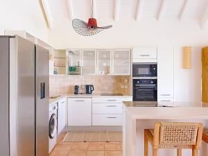 una cucina con mobili bianchi e un frigorifero in acciaio inossidabile di Sable Bleu Elegant 2-Bedroom Oceanfront Apartment a Orient Bay Altre 18 foto