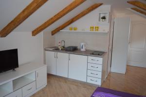 a kitchen with white cabinets and a flat screen tv at Apartments Coso Zlatne njive bb in Kotor
