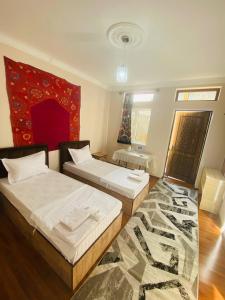 Un dormitorio con dos camas y una alfombra. en Hotel Mashhur, en Bukhara