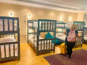 a woman with a backpack walking through a room with bunk beds at Mandarine hostel in Tirana