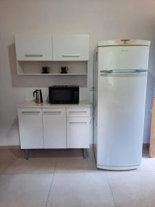a white kitchen with a refrigerator and a microwave at Sítio Jabuticabeira in Santo Antônio do Pinhal