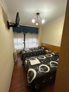 a group of four beds in a room at Pensión Arcano in Arzúa +7 photos
