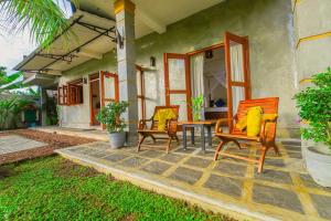 a patio with three chairs and a table with yellow cushions at Cinnamon Villas in Ambalangoda
