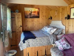 una camera da letto con un letto in una stanza di legno di 1 Bedroom Cabin Sleeps 2 Private Garden WiFi a Camelford