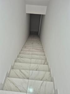 a staircase in a room with white walls and marble floors at Condomínio Tribu 02 in Caruaru