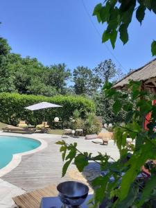 a pool with chairs and an umbrella next to a house at L'Armandine in Saint-Marcel-Bel-Accueil