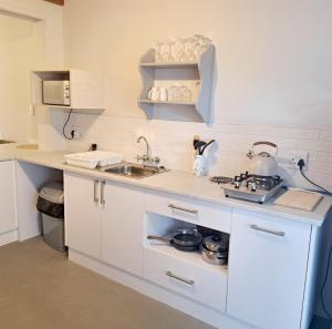a white kitchen with a sink and a stove at 177 on Church in Oudtshoorn