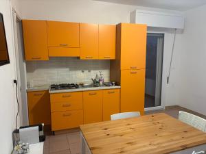 a kitchen with orange cabinets and a wooden table at Case al mare in Salento B12 in Marina di Leuca