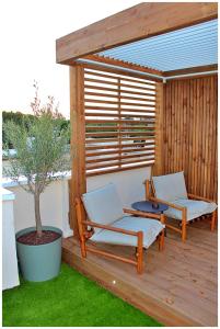 una terrazza in legno con 2 sedie e un albero di Appartement standing avec spa, terrasse & calme absolu, Entre mer et lac, La Grande Motte a La Grande-Motte Altre 11 foto