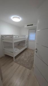 a small room with a white bunk bed and a door at Azur Perla in Sarajevo