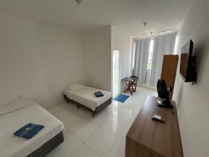 a room with two beds and a television in it at Shalom Flat Hotel in Pará de Minas