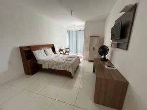 a bedroom with a bed and a flat screen tv at Shalom Flat Hotel in Pará de Minas