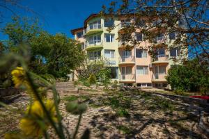 a building on a hill with flowers in front of it at Family Hotel Perla in Golden Sands
