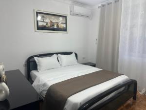 ベラトにあるTwinstay - Aura Apartmentのベッドと壁に絵が飾られた寝室