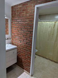 a brick wall in a bathroom with a sink and a shower at B&Z Departamentos in Federación