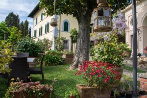 un giardino con fiori e un albero e una casa di Villa Parri Residenza D'epoca a Pistoia