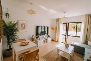 een woonkamer met een bank en een tv bij Playa y Palmera in Corralejo