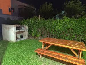 a wooden bench sitting in the grass next to a hedge at B&Z Departamentos in Federación