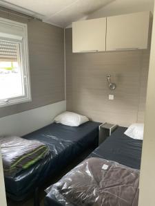 乐巴凯尔斯Azur Premium Climatisé 4 étoiles au camping la presqu'île du Barcarés vue imprenable的一间带窗户的小房间里有两张床
