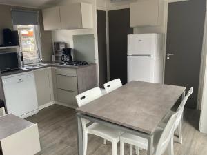 乐巴凯尔斯Azur Premium Climatisé 4 étoiles au camping la presqu'île du Barcarés vue imprenable的配有桌椅和冰箱的厨房