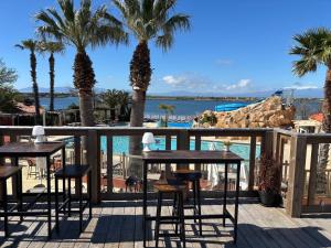 乐巴凯尔斯Azur Premium Climatisé 4 étoiles au camping la presqu'île du Barcarés vue imprenable的有桌子、棕榈树和水的露台