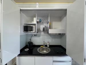 Una pequeña cocina con fregadero y microondas. en White Tower-Studio, en Mamaia