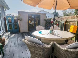 a patio with a table and chairs and an umbrella at Sailaway in Carbis Bay