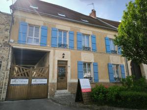 Una casa antigua con ventanas azules y un garaje. en Gîte Champagne Philippe Moutardier - Chambre Cépage, en Chézy-sur-Marne