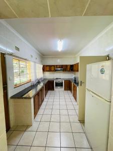 a kitchen with a white refrigerator and a tile floor at Paradise Palms in Francistown