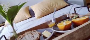 a tray of food with bread and oranges on a bed at Studio montagne in Aulus-les-Bains