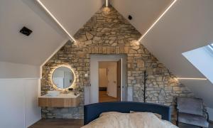 a bedroom with a stone wall with a bed and a sink at Au bout du bois in Jalhay