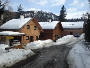 ein Haus mit Schnee am Straßenrand in der Unterkunft Turracher Berghütte in Turracher Hohe