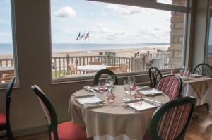 a dining room with a table and a view of the beach at Logis Hotel Du Casino in Vierville-sur-Mer