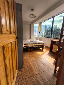 a bedroom with a bed and a large window at Pitusiray Sanctuary House in Calca
