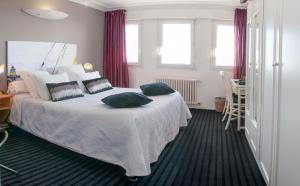 a bedroom with a white bed with pillows on it at Logis Hotel Du Casino Restaurant Le Mathelia in Vierville-sur-Mer