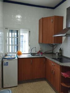 a kitchen with wooden cabinets and a white refrigerator at Casa Athenea in Conil de la Frontera