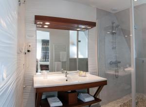 a bathroom with a sink and a shower at Logis Hotel Du Casino Restaurant Le Mathelia in Vierville-sur-Mer