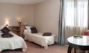 a hotel room with two beds and a table at Logis Hotel Du Casino Restaurant Le Mathelia in Vierville-sur-Mer