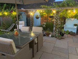 eine Terrasse mit Tisch und Stühlen unter einer Pergola in der Unterkunft St Catherines Cottage The Old Schoolhouse in Long Melford